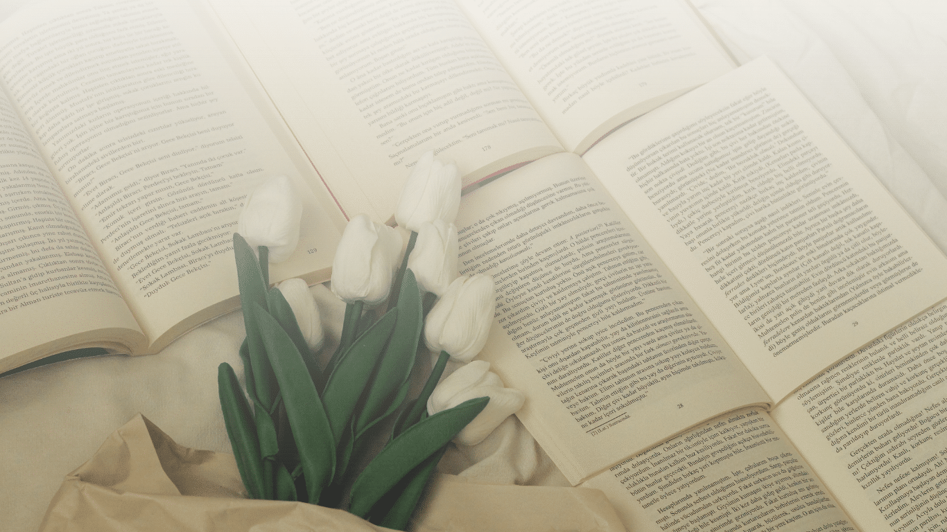 Book formatting Process | Books laid flat with buddle of white tulips on table.